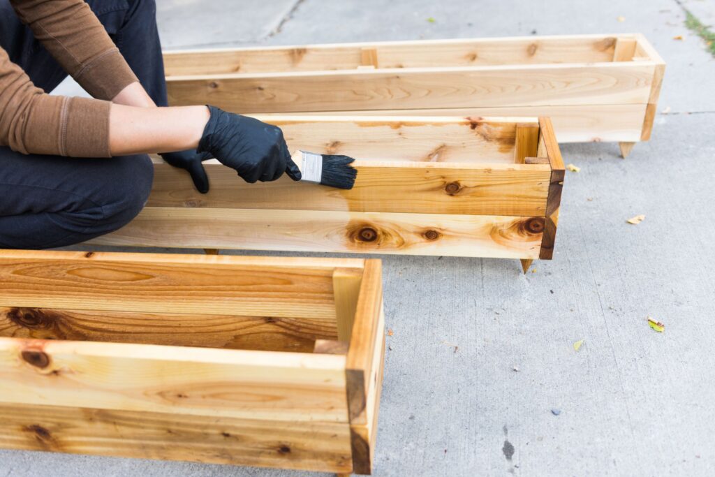 Femme qui peint des jardinières en bois